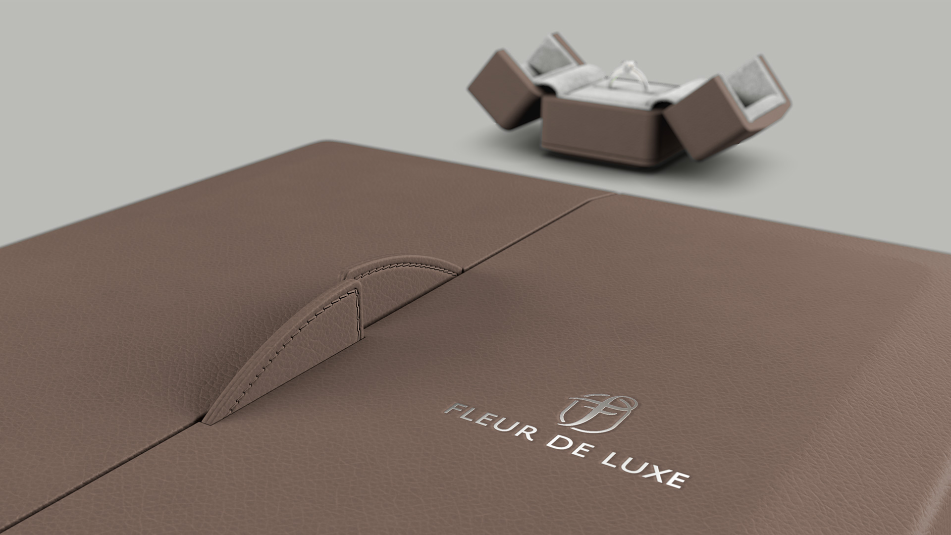 Geschlossenes Etui mit zweigeteiltem Deckel mit Magnetverschluss in Braun und Grau. Im Hintergrund ein offenes Ring-Etui klein.