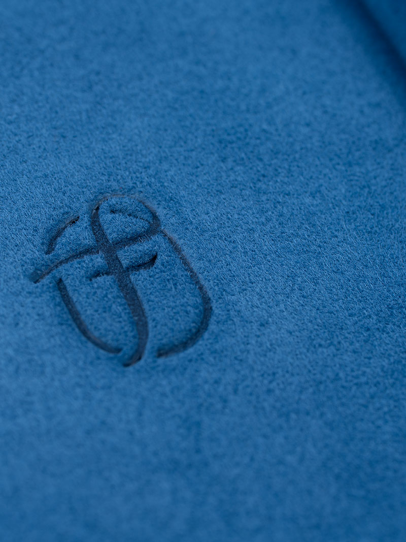 Détail d'un logo en relief Fleur de Luxe sur du velours bleu véritable